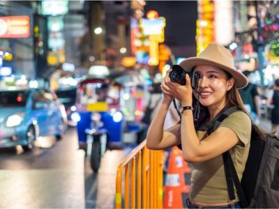Tourist photographing in a Bangkok street at night.