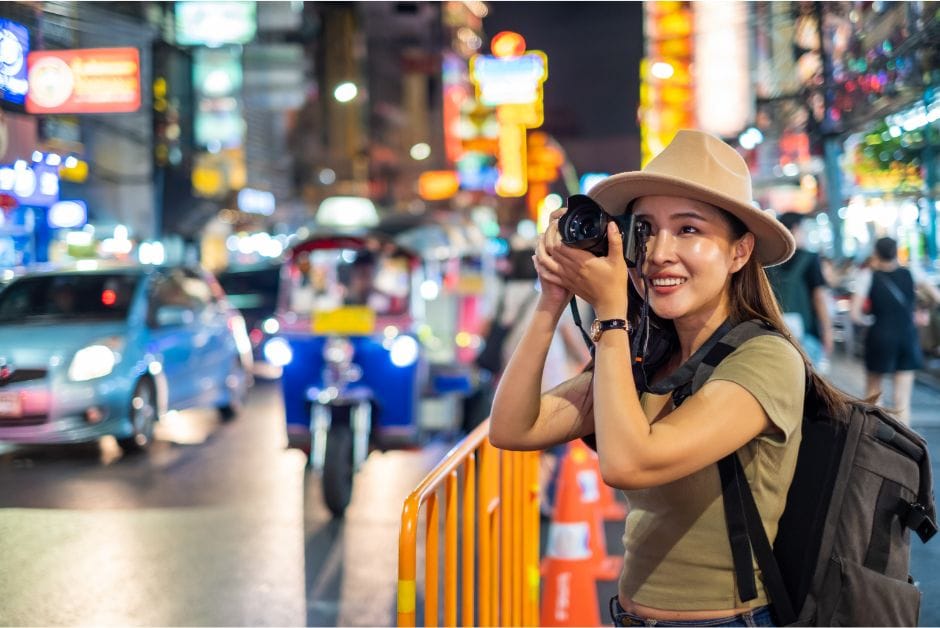 Tourist photographing in a Bangkok street at night.