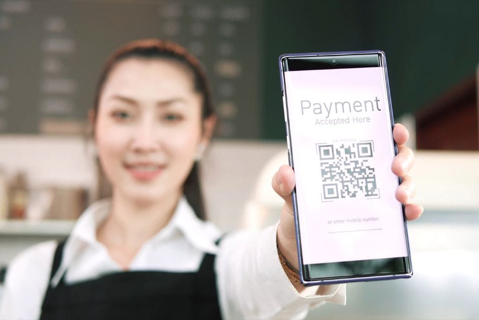 Barista showing QR code for payment on mobile phone.