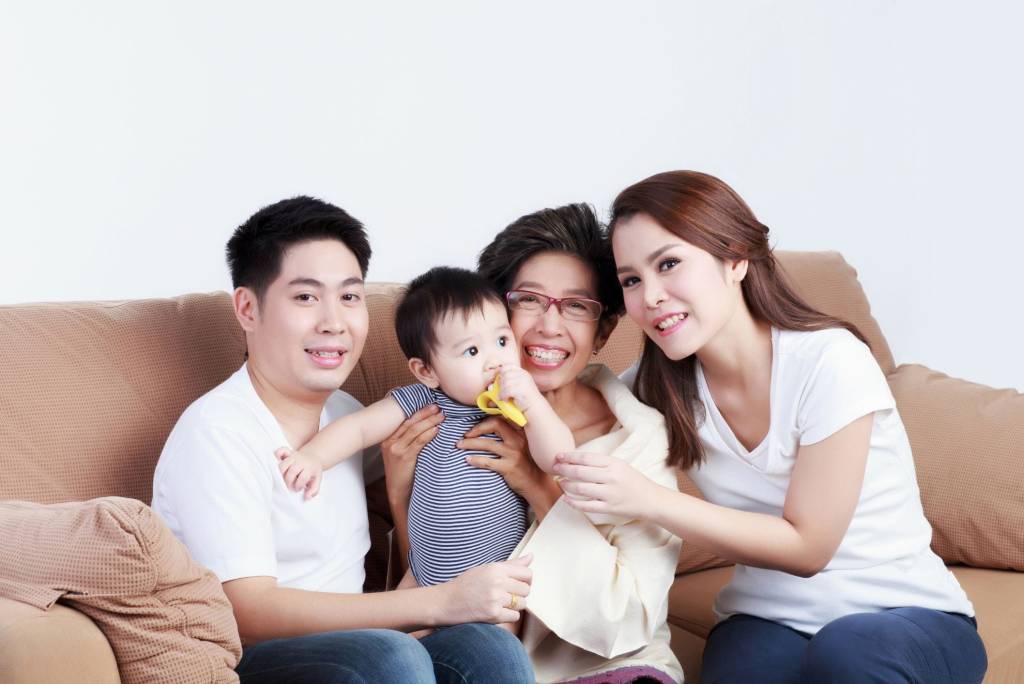 A Thai family sitting together on sofa at home.