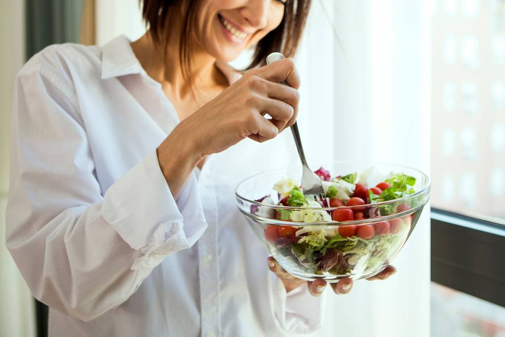 Woman eating a bowl of salad.