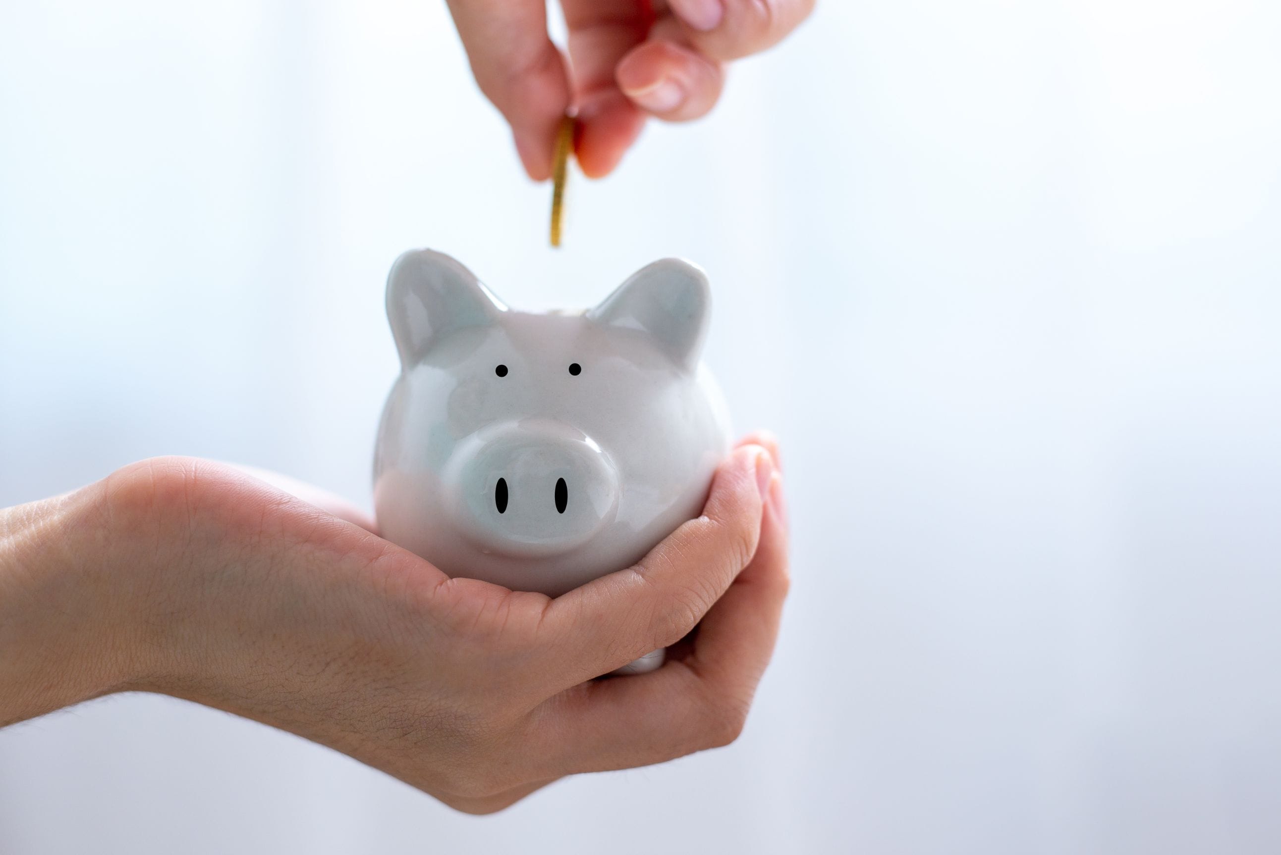 Person dropping coin into piggy bank.