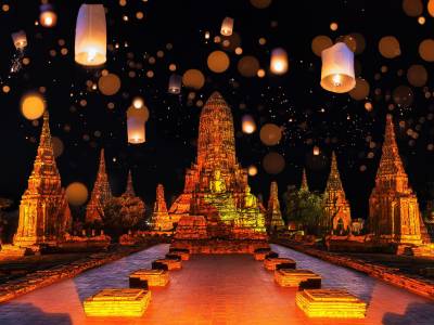 Floating lanterns against temple background at night during Loy Krathong festival in Ayutthaya, Thailand.