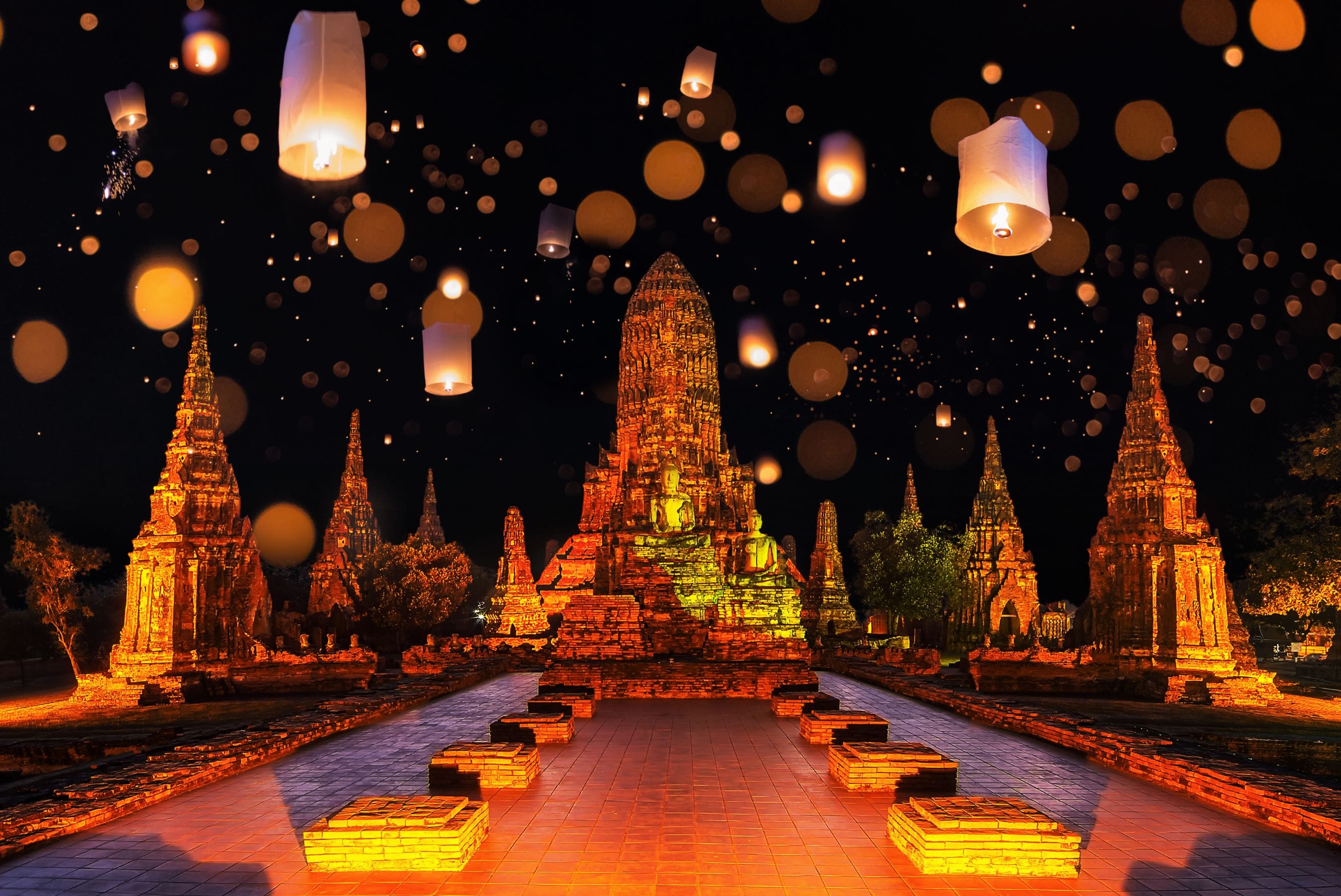 Floating lanterns against temple background at night during Loy Krathong festival in Ayutthaya, Thailand.