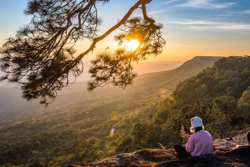 Person sitting on mountain in Phu Kradueng National Park, Thailand.