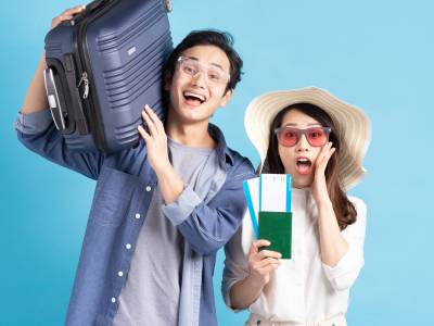 Asian couple with suitcase and flight tickets.