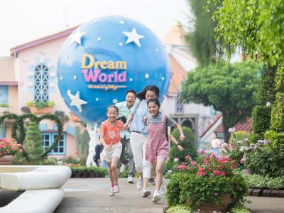 Family happily running through Dream World theme park, Thailand.