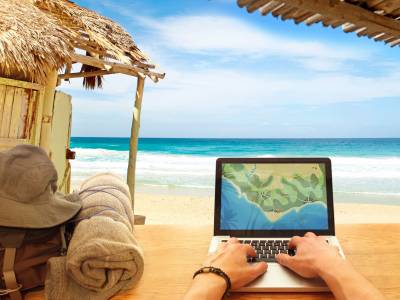 Digital nomad working on laptop on beach.