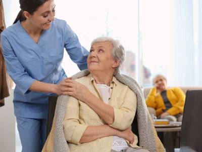 Assistant helping elderly patient in nursing home.