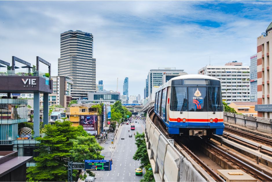 BTS Skytrain passing modern towers in Bangkok.