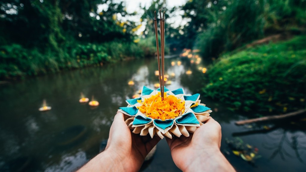 Man holding krathong at Loy Krathong festival in Thailand.