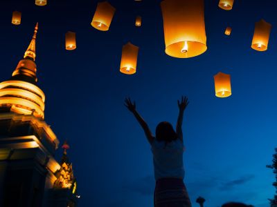 Lanterns floating up into night sky at Yi Peng festival in Thailand.