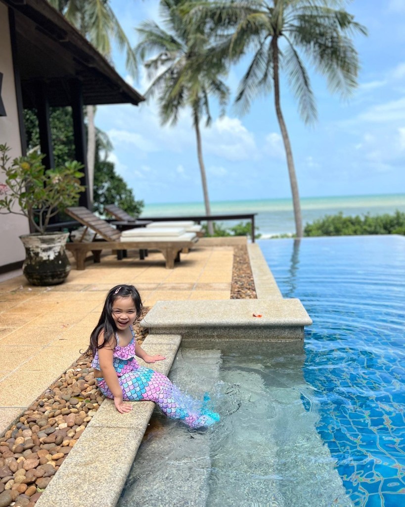 Young girl sitting on steps of pool at Pimalai Resort & Spa, Koh Lanta in Thailand.