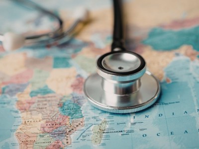 A stethoscope on the map of the world to represent global wellness.