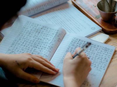 A person is writing out the characters of an Asian language.