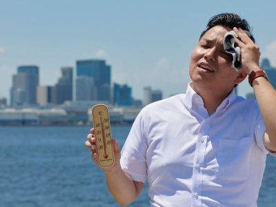 Man mopping his brown in heat while holding thermometer.