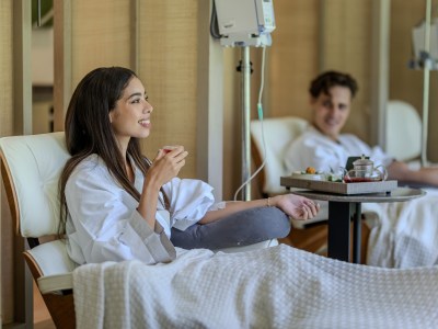 A couple are reclining while receiving an infusion.