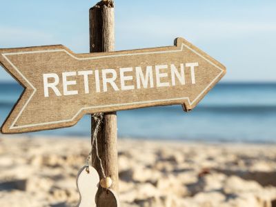 A wooden 'RETIREMENT' sign in the sand at a beach.