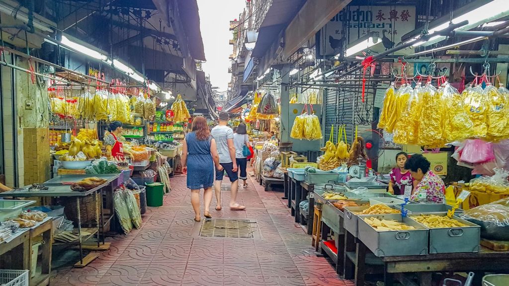 Tourists walking through an outdoor food market in Thailand.