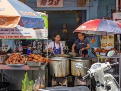 Two women prepare street food in Thailand.