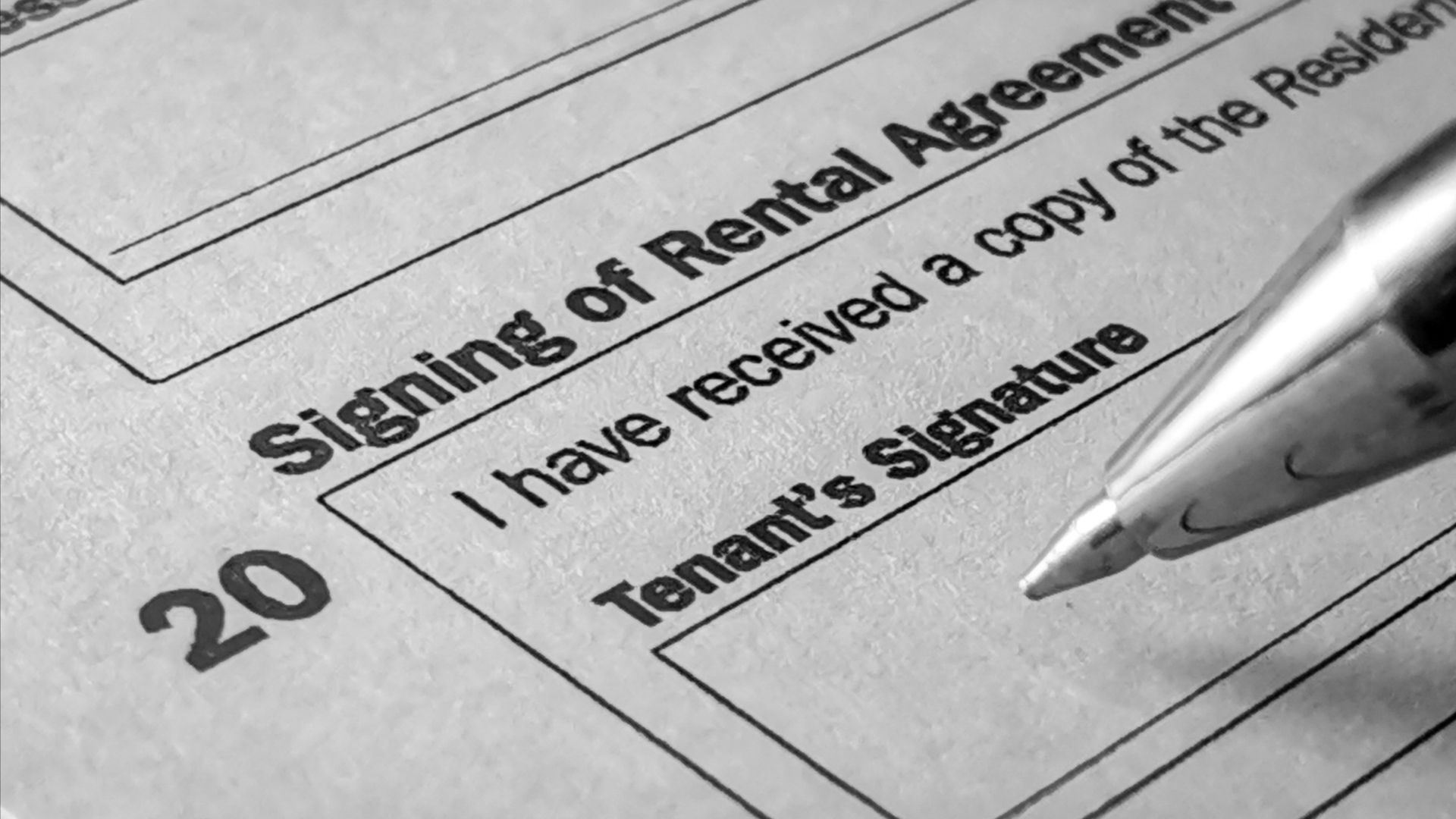 Close-up of a rental agreement being signed with property keys nearby